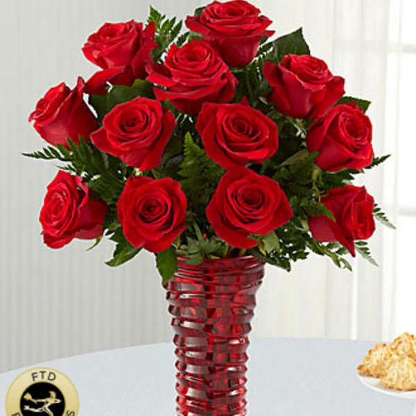 Red roses arranged in a tall red glass vase