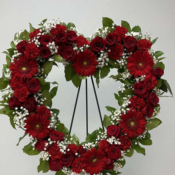 Heart-shaped floral wreath with red roses, gerbera daisies, and white baby's breath