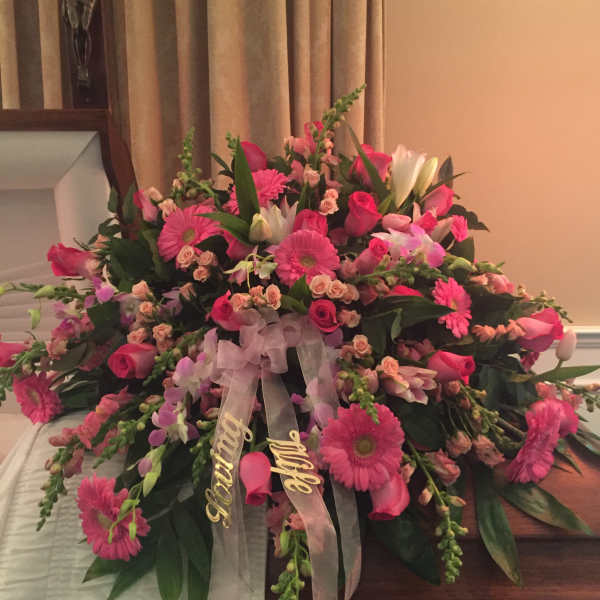 Pink and white floral casket spray with ribbon streamers