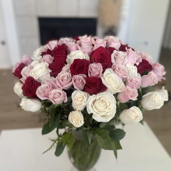 Bouquet of pink, red, and white roses in a clear glass vase