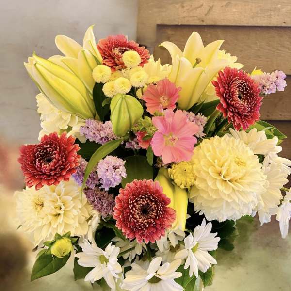 Mixed bouquet of lilies, chrysanthemums, and daisies in a glass vase
