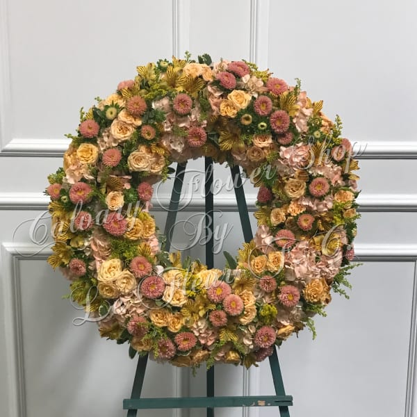 Large floral wreath on an easel with pink and peach blooms