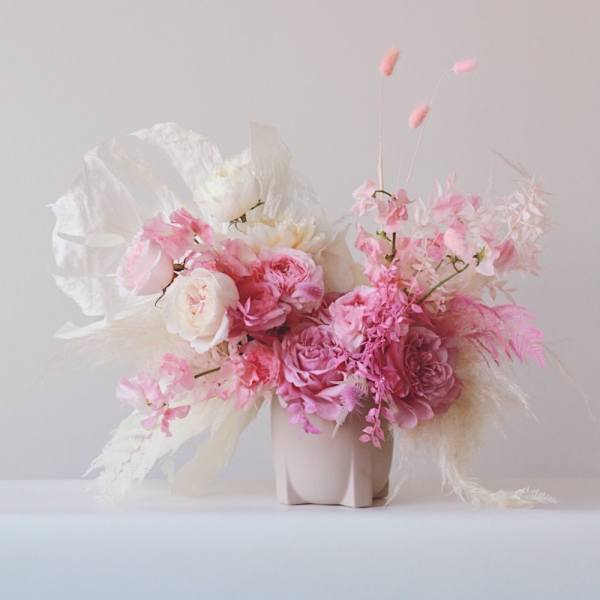 Pink and white floral arrangement in a pale vase