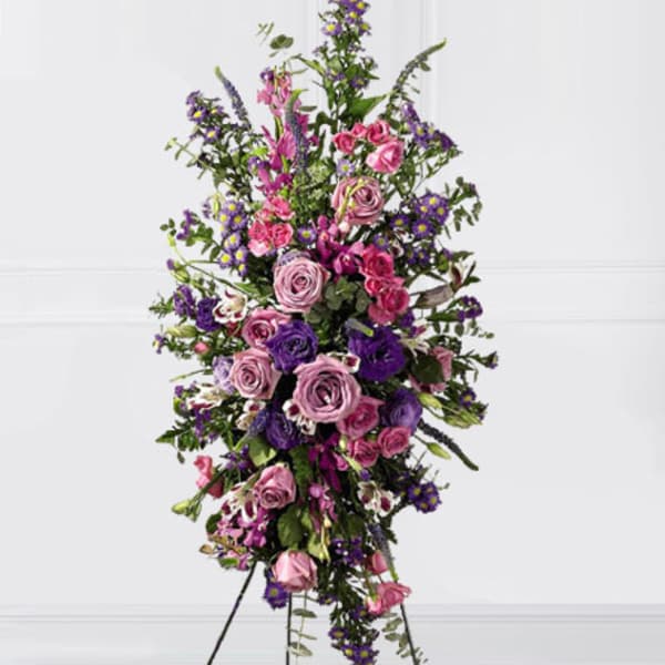 Tall standing spray of pink and purple flowers on a white background