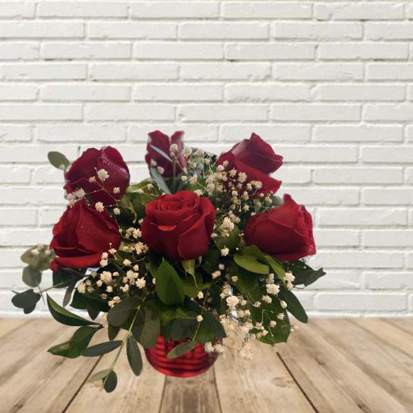 Red roses in a red glass vase with baby's breath