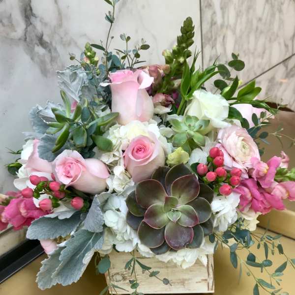 Pink roses and white blooms arranged with succulents in a wooden box