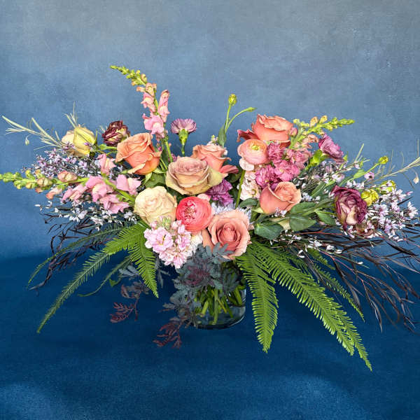 Mixed bouquet of pink and peach flowers in a glass vase
