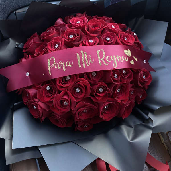 Bouquet of red roses wrapped in black paper with a pink ribbon