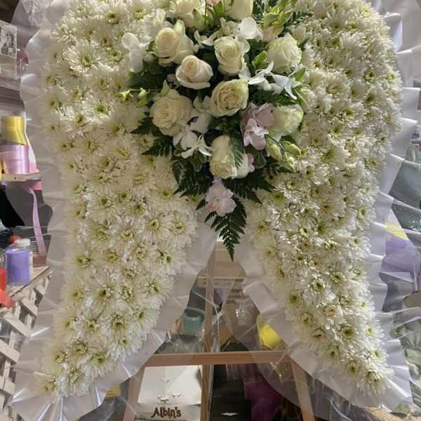 White floral standing spray with roses and chrysanthemums on an easel