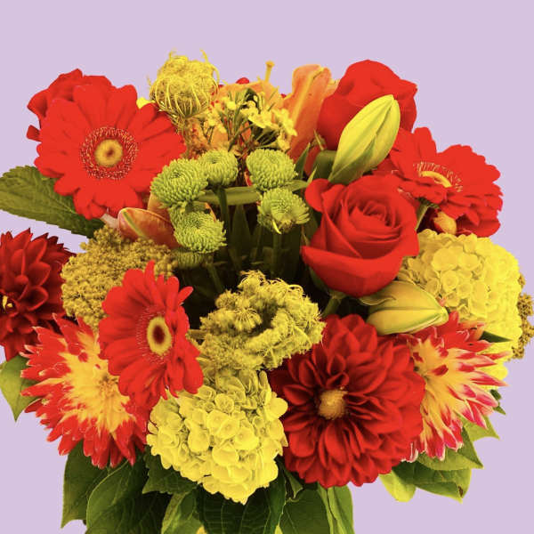 Bright mixed bouquet of red and yellow flowers in a glass vase
