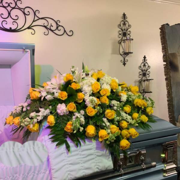 Large yellow and white floral spray on a casket