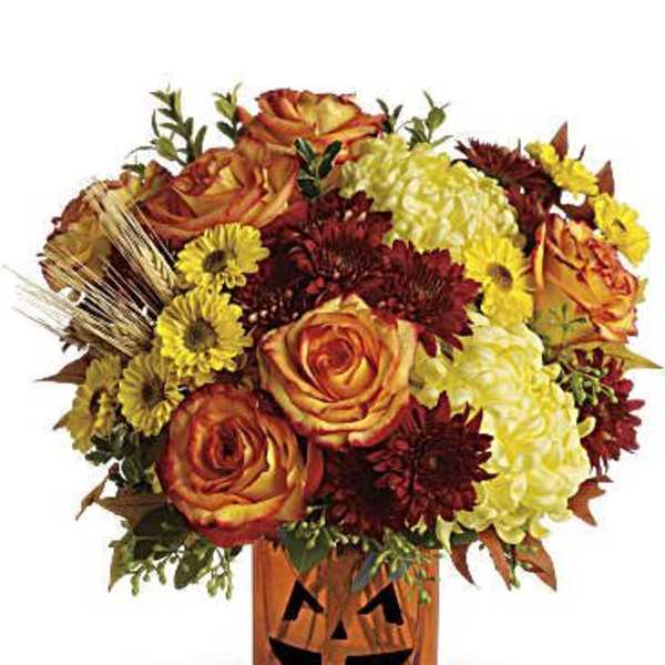 Orange roses and yellow chrysanthemums in a jack-o'-lantern vase