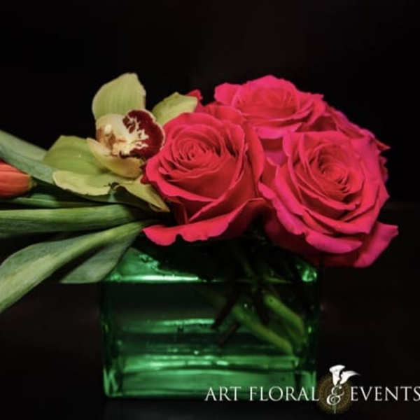 Pink roses and tulips arranged in a green glass vase