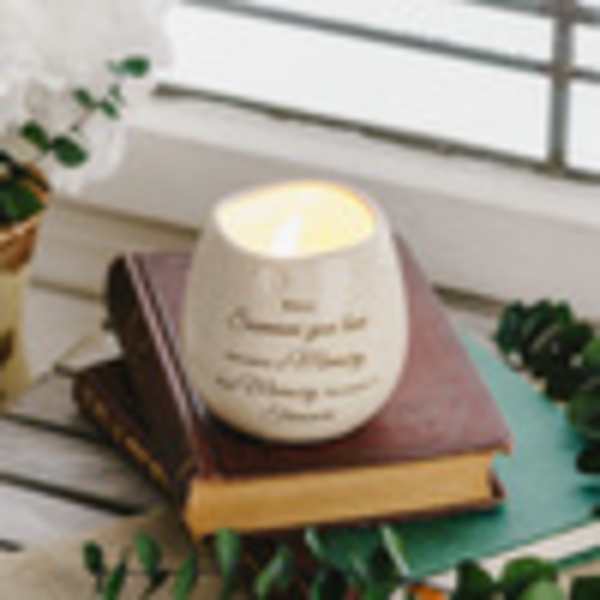 White candle in a ceramic holder resting on stacked books