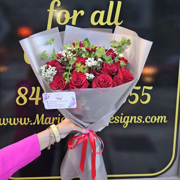 Bouquet of red roses with small white filler flowers in gray wrap