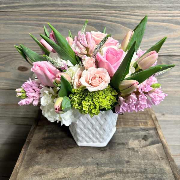 Pink and white floral arrangement in a white woven vase