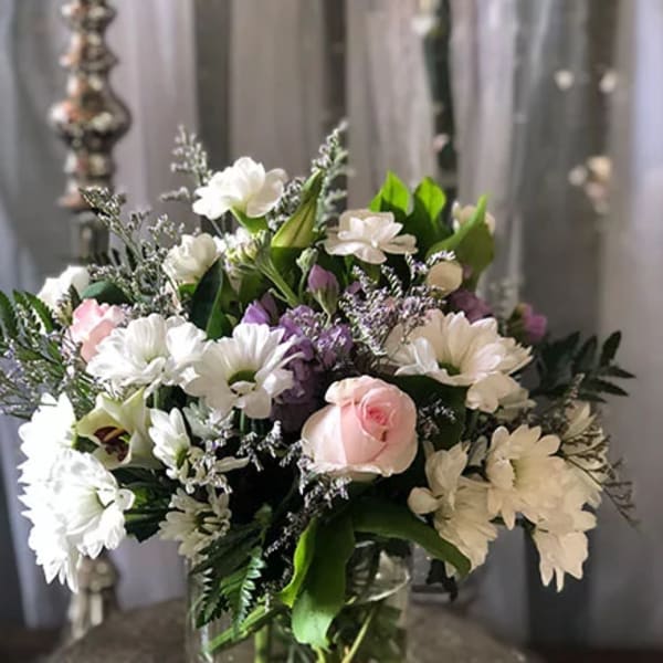 Mixed white, pink, and purple flowers in a clear glass vase