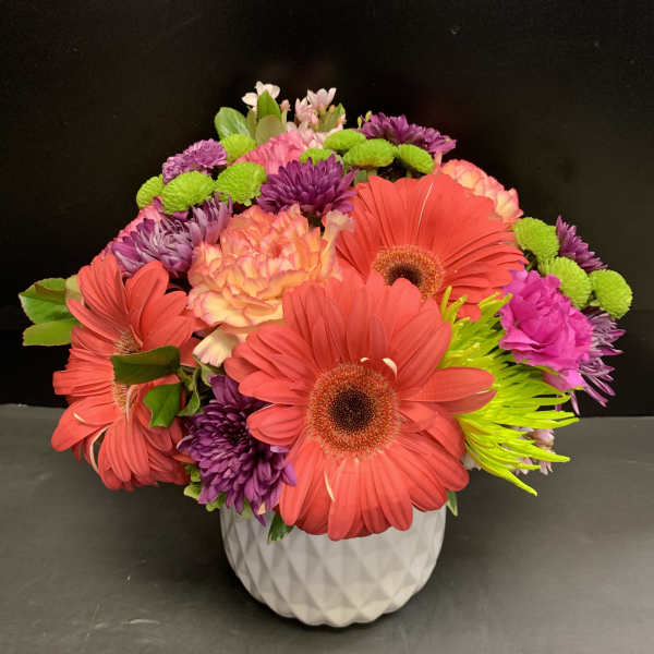 Bright mixed flower arrangement in a white textured vase