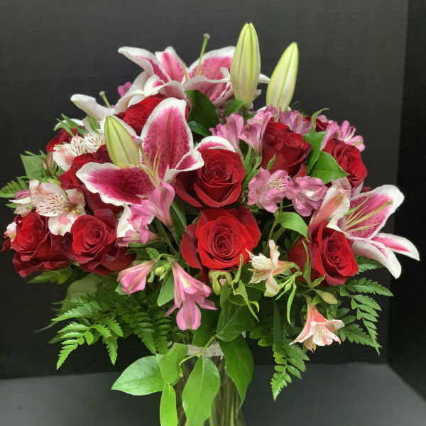 Bouquet of red roses and pink lilies in a glass vase