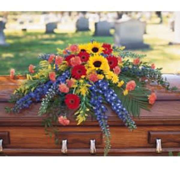 Colorful flower spray on a wooden casket in a cemetery