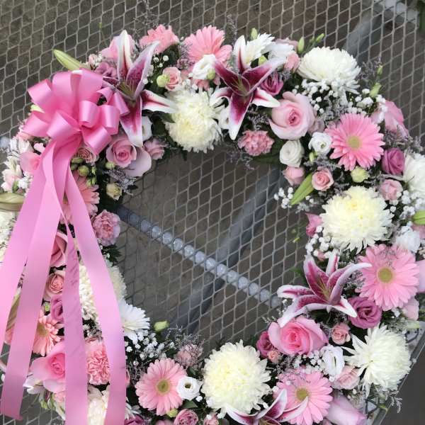 Pink and white floral wreath with a large pink ribbon bow