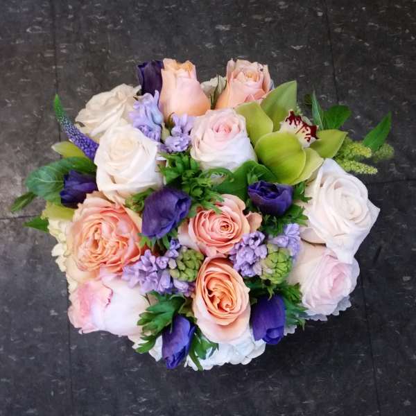Bouquet of pastel roses, purple blooms, and green orchids