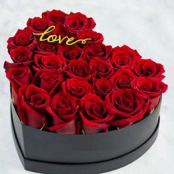 Heart-shaped box of red roses with a gold "love" topper
