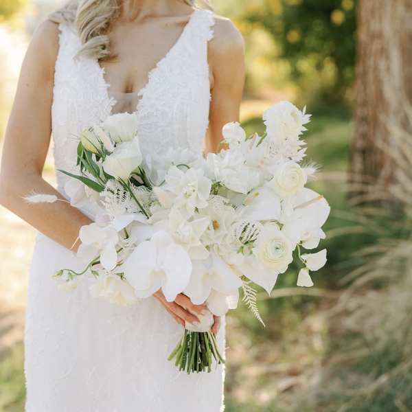 Bride holding a white bouquet with orchids and ranunculus