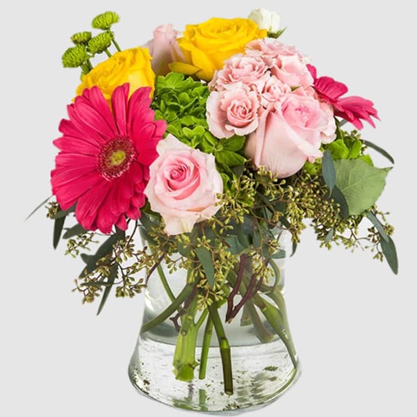 Pink and yellow roses with a hot pink gerbera daisy in a glass vase