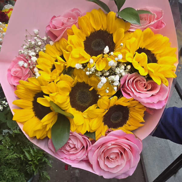 Bouquet of yellow sunflowers and pink roses wrapped in pink paper