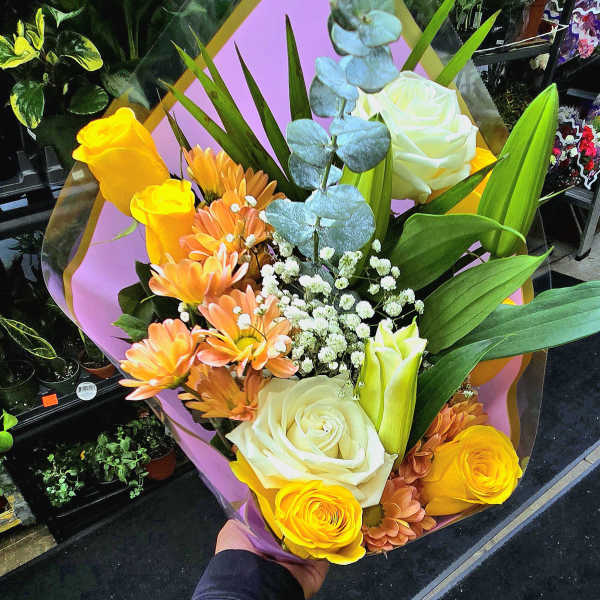 Bouquet of yellow and white roses with orange daisies and blue eucalyptus