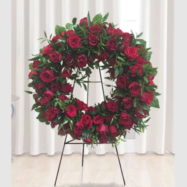 Circular wreath of red roses on a black stand