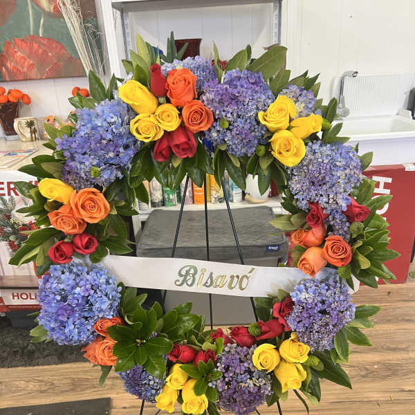 Large floral wreath with multicolored roses and blue hydrangeas on a stand