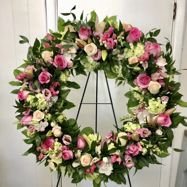 Large pink and white floral wreath on a black stand
