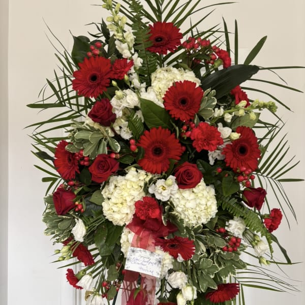 Standing floral spray with red gerberas and roses, white hydrangeas, and greenery