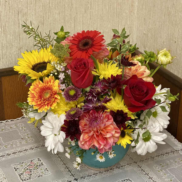 Colorful mixed bouquet in a turquoise vase with roses and daisies
