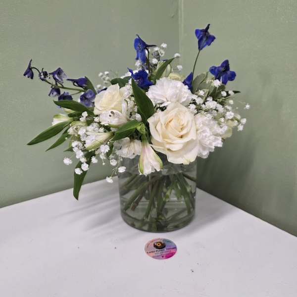 White roses and blue flowers in a clear glass vase