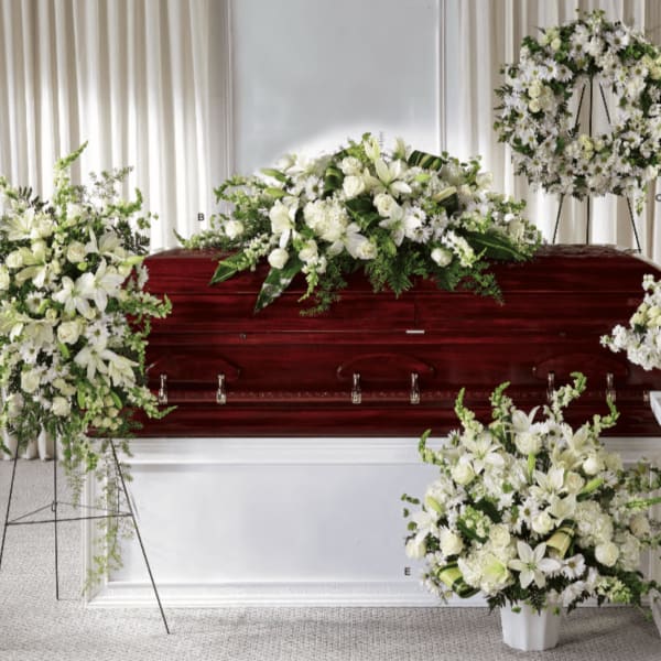 White floral funeral arrangements around a casket