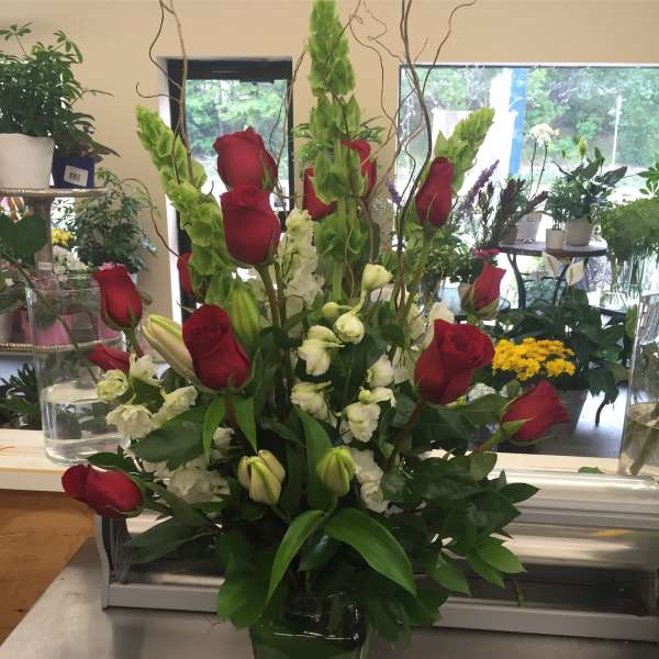 Red roses and white flowers arranged in a glass vase