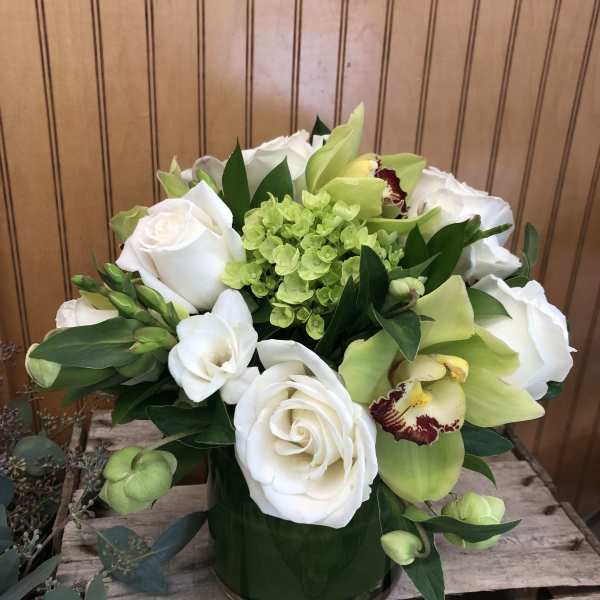 White roses and green orchids in a glass vase