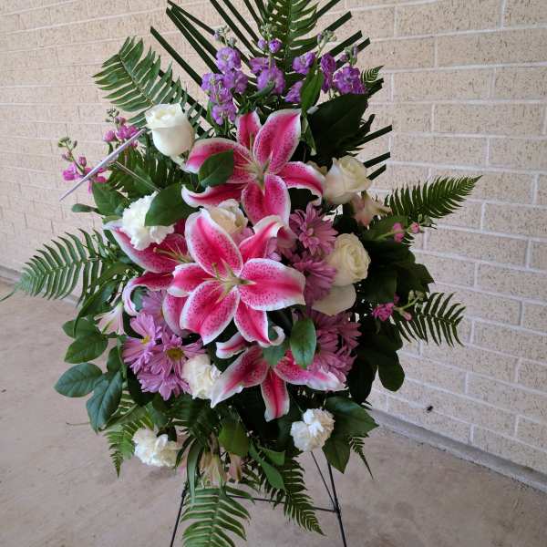 Standing spray with pink lilies, white roses, and purple flowers