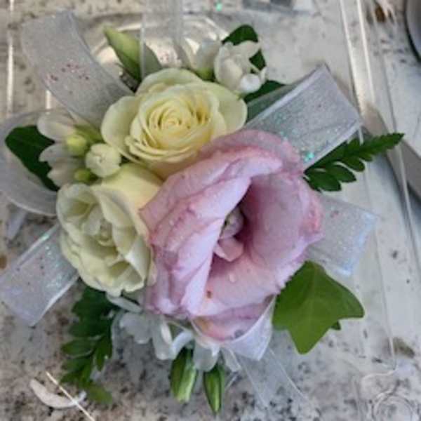 Small bouquet of white and pink flowers wrapped in clear ribbon