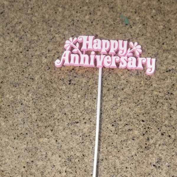 Pink "Happy Anniversary" cake topper on a white stick