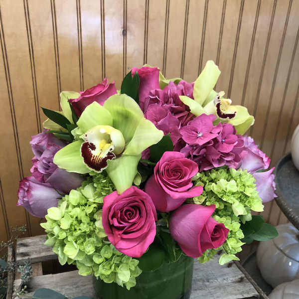 Pink roses and green hydrangeas in a glass vase with pale green orchids