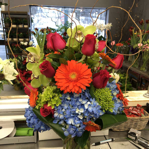 Bright mixed bouquet in a glass vase with roses, orchids, gerbera daisies, and hydrangeas