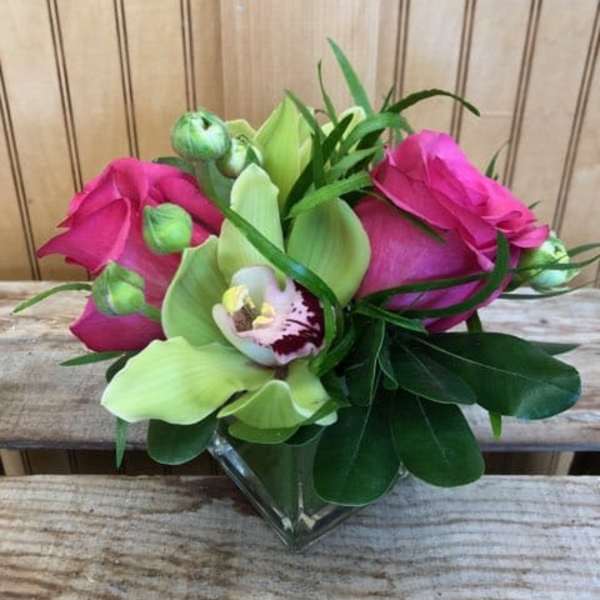 Pink roses and green orchids in a clear glass vase