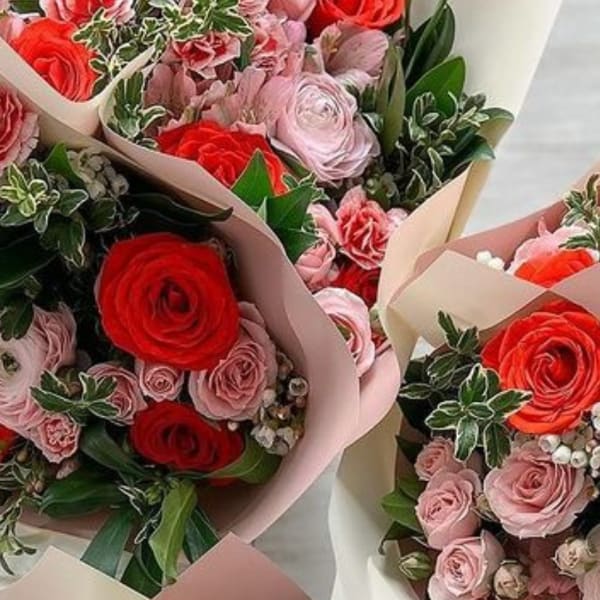 Several bouquets of pink and red roses wrapped in pastel paper