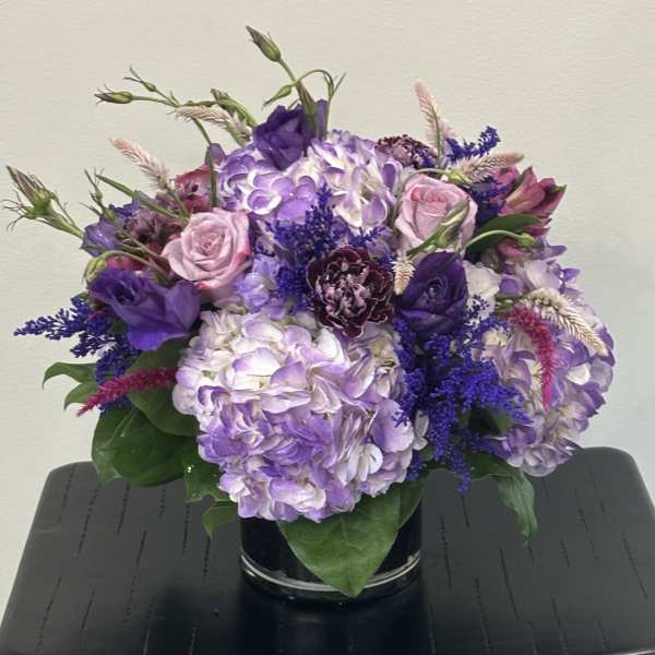 Purple and pink floral arrangement in a black vase
