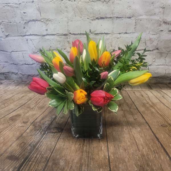 Colorful tulip arrangement in a square glass vase