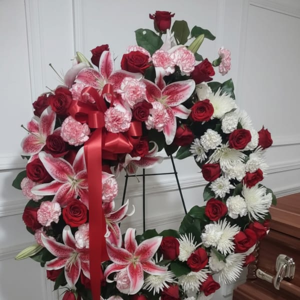 Heart-shaped floral wreath with red roses, pink lilies, and white chrysanthemums